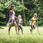 Kinder, die mit ihrer Mutter durch den Wald laufen