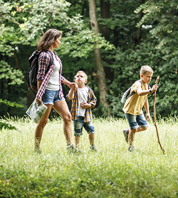 Kinder, die mit ihrer Mutter durch den Wald laufen